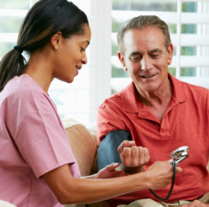 A woman is checking the blood pressure of an older man.